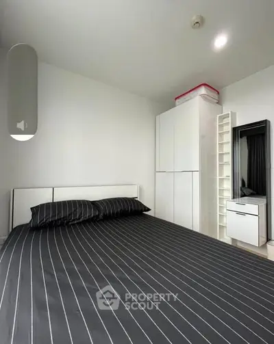 Modern bedroom with sleek black bedding and minimalist white furniture.