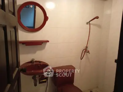 Cozy bathroom with red fixtures and shower in a compact space