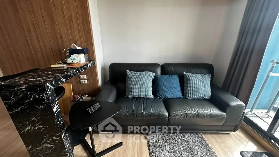 Modern living room with sleek black leather sofa and marble bar counter, featuring a cozy balcony view.