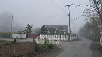 Charming countryside house with white picket fence on a foggy day