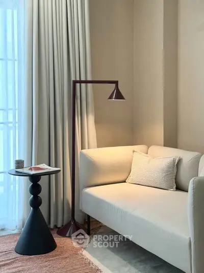 Elegant living room with modern sofa, stylish floor lamp, and chic side table near large window.