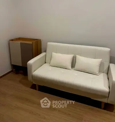 Cozy living room with modern white sofa and wooden flooring, perfect for relaxation.