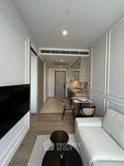 Modern living room with sleek furniture and open kitchen layout in a stylish apartment.