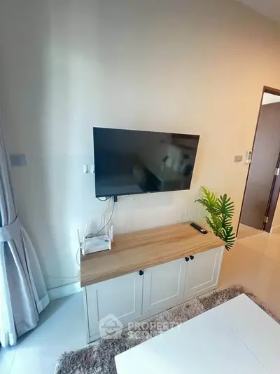 Modern living room with wall-mounted TV and stylish cabinet in a cozy apartment.