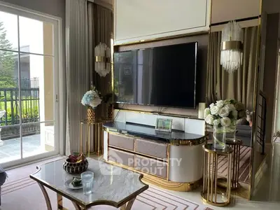 Luxurious living room with elegant decor and large TV, featuring a stylish coffee table and garden view.