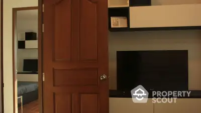 Modern living room with sleek TV unit and wooden door, showcasing contemporary interior design.