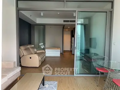 Modern open-plan living room with glass sliding doors and stylish furniture in a contemporary apartment.