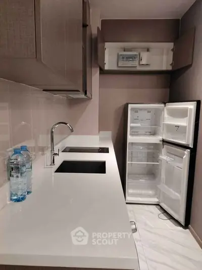 Modern kitchen with sleek countertops and open fridge in compact layout