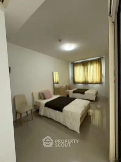Spacious twin bedroom with modern decor and ample natural light.