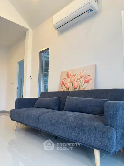 Modern living room with stylish blue sofa and wall art, featuring sleek air conditioning unit.