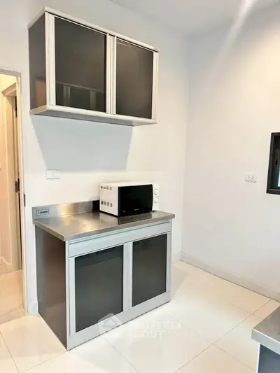 Modern kitchen with sleek cabinets and microwave on stainless steel countertop