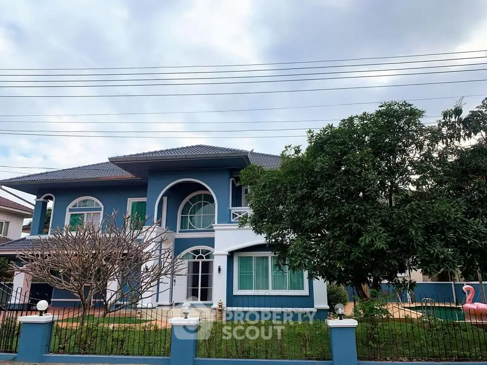 Charming two-story blue house with lush garden and elegant facade