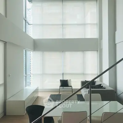 Modern living room with high ceilings and large windows in a stylish apartment.