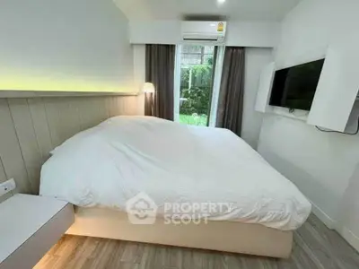 Cozy bedroom with modern decor, featuring a large bed, wall-mounted TV, and garden view.