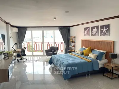 Spacious bedroom with modern decor and balcony view, featuring a cozy workspace and stylish furnishings.