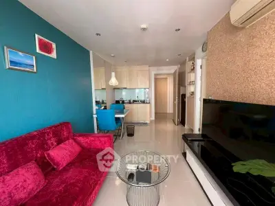 Modern living room with vibrant red sofa and open kitchen layout, featuring sleek design and contemporary decor.