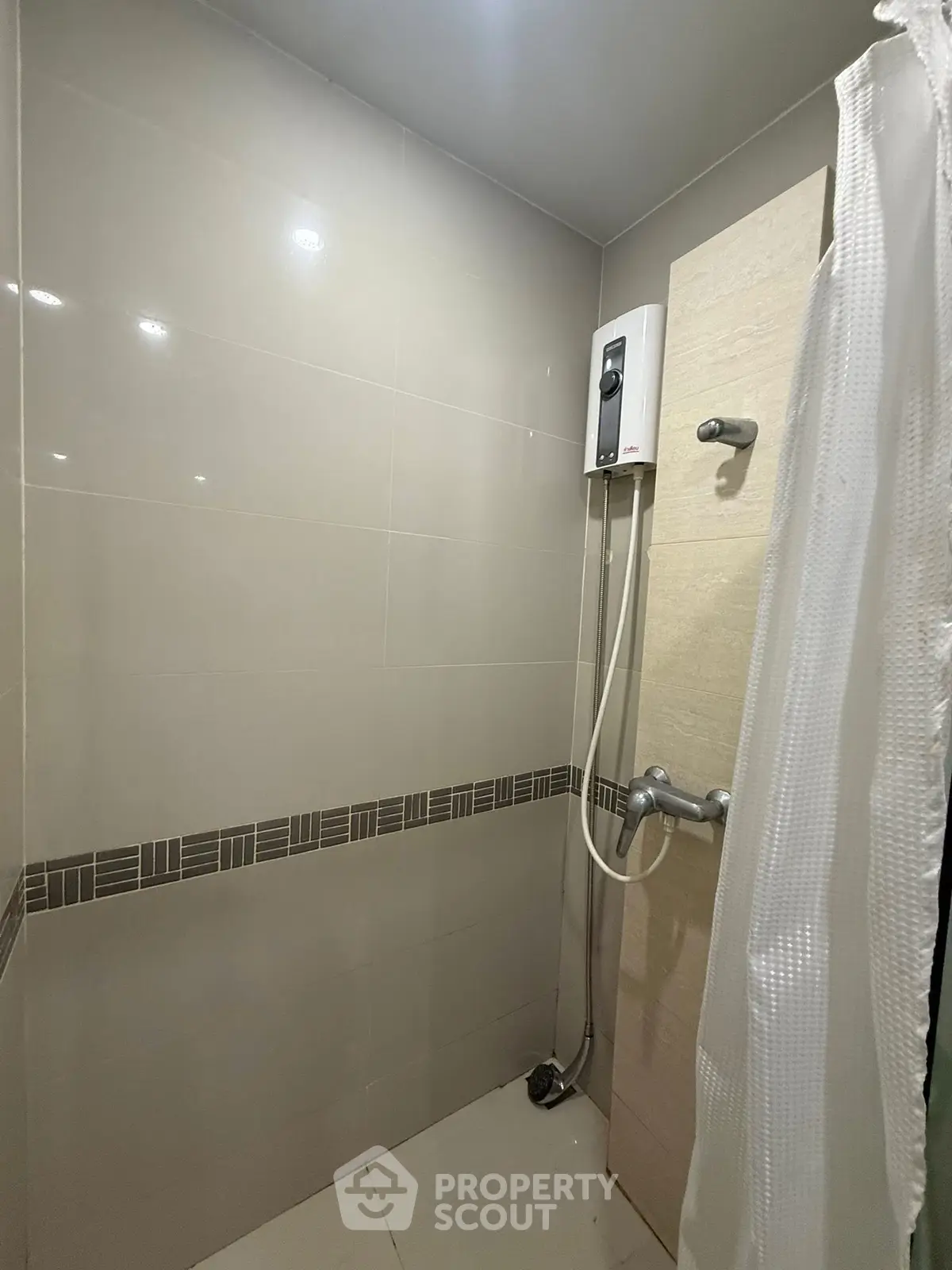Modern bathroom with shower and water heater in sleek tiled design.