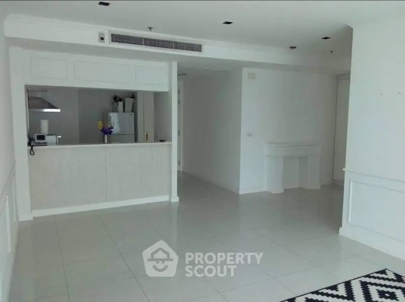 Spacious open-plan living area with modern kitchen and tiled flooring.