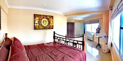 Spacious bedroom with elegant decor and large windows offering natural light.