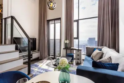 Luxurious modern living room with high ceilings and city view, featuring elegant decor and large windows.