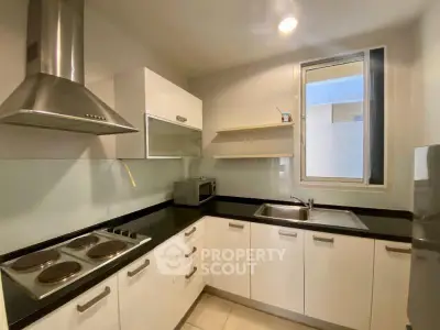 Modern kitchen with sleek cabinetry and electric stove in a cozy apartment.