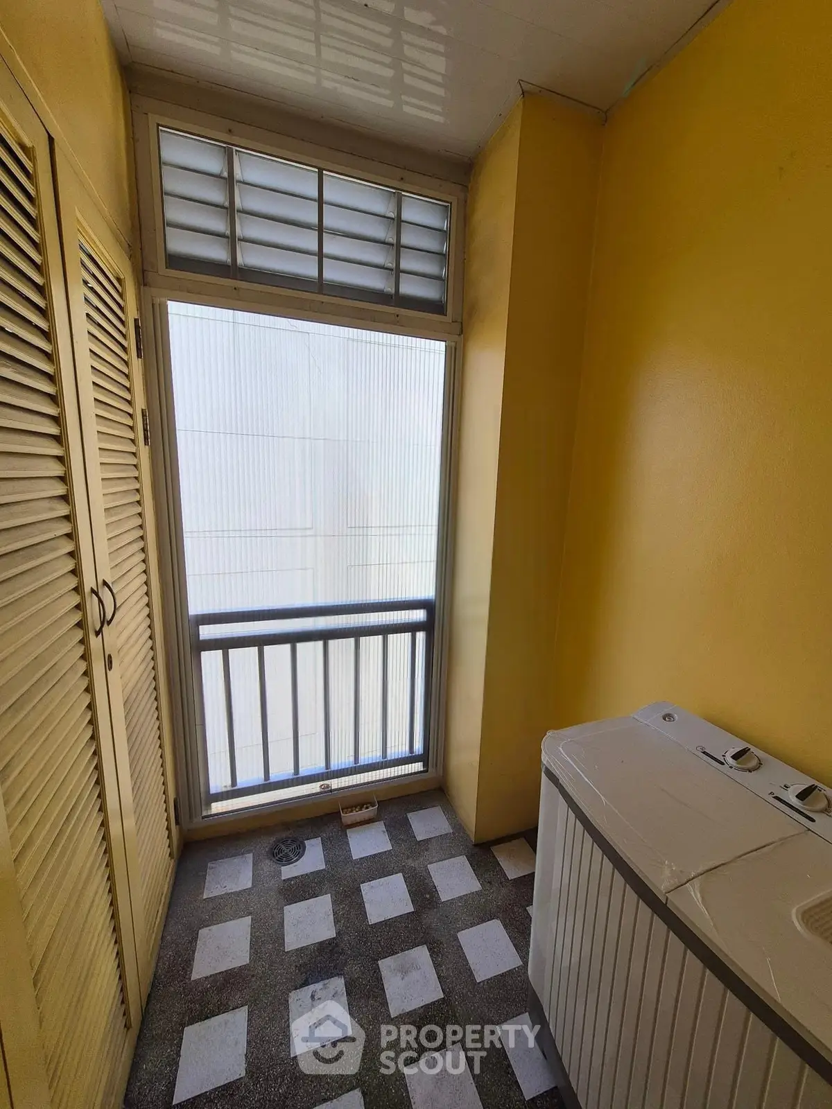 Compact laundry area with washing machine and bright yellow walls, perfect for efficient use of space.