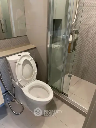 Modern bathroom with sleek shower and toilet in a compact design.