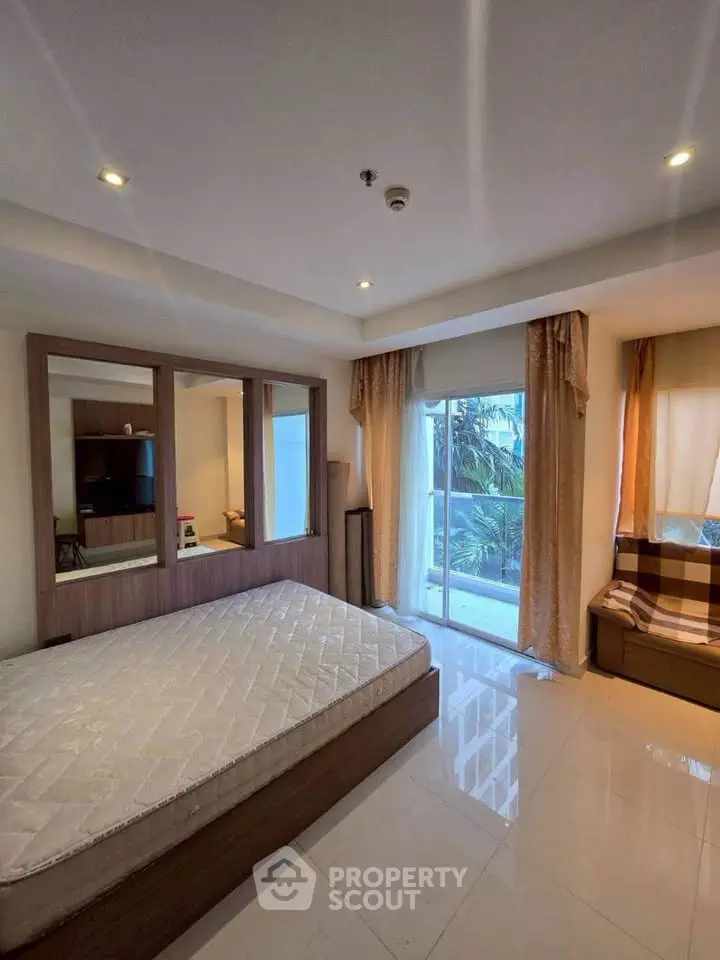 Spacious bedroom with large windows and modern furnishings in a well-lit apartment.