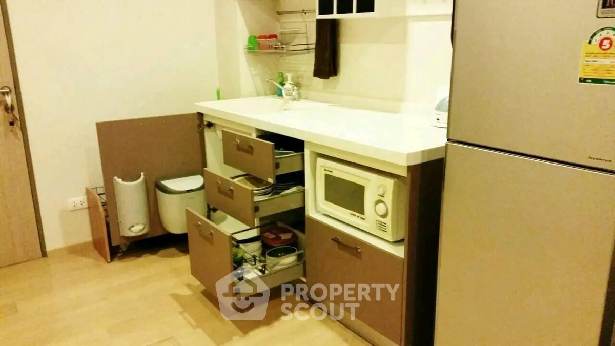 Modern kitchen with open cabinets and microwave, featuring sleek design and ample storage space.