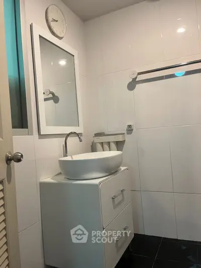 Modern bathroom with sleek white sink and wall-mounted mirror.