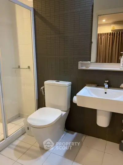 Modern bathroom with sleek fixtures and glass shower enclosure in a contemporary apartment.