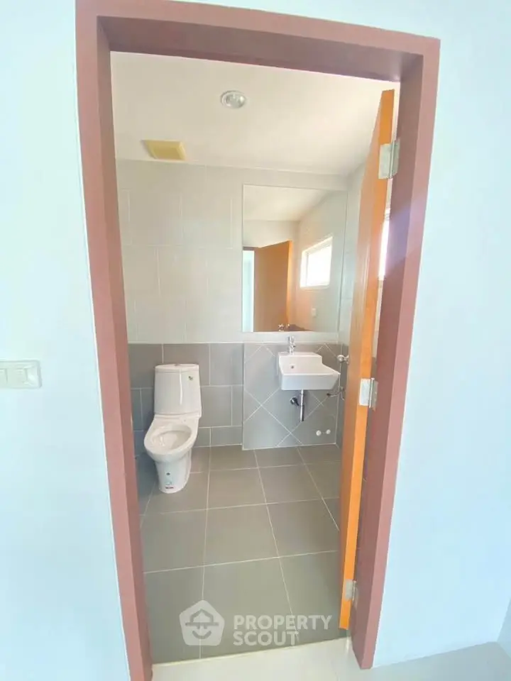 Modern bathroom with sleek design and neutral tiles, featuring a toilet and sink.