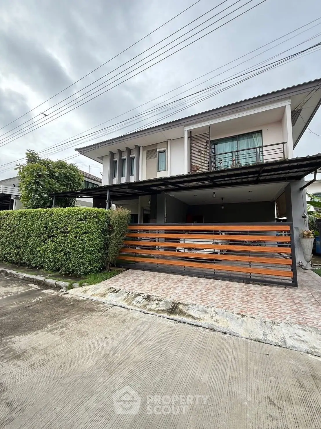 Modern two-story house with balcony and driveway in a suburban neighborhood.