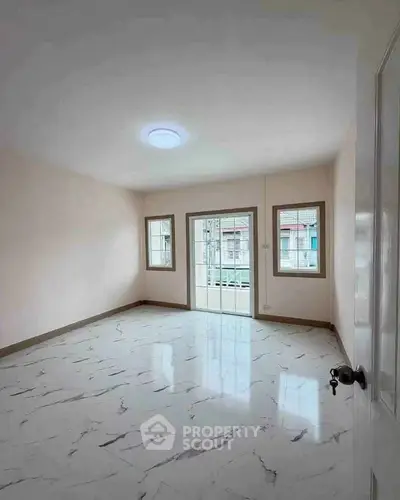 Spacious empty room with marble flooring and large windows for natural light.