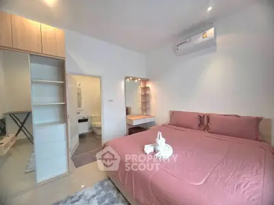 Cozy bedroom with pink bedding, mirrored wardrobe, and air conditioning unit.