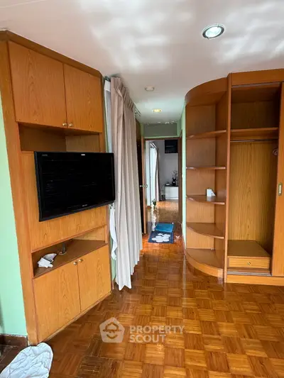 Spacious living area with wooden flooring and built-in storage, perfect for modern living.