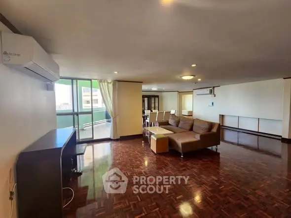 Spacious living room with elegant wooden flooring and modern furniture in a bright apartment.