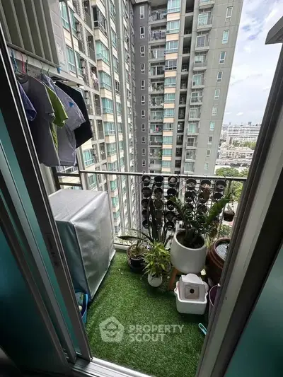 Charming balcony with city view and lush greenery in modern high-rise apartment.
