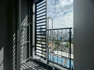 City view from a high-rise balcony with metal railing and drying rack.