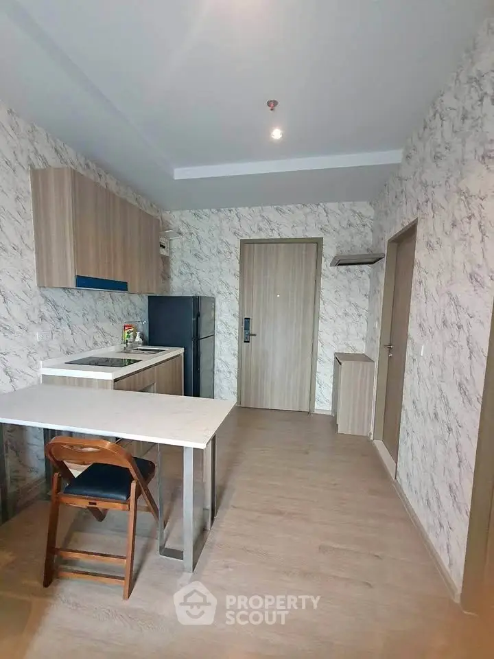 Modern kitchen with marble walls and compact dining area in stylish apartment