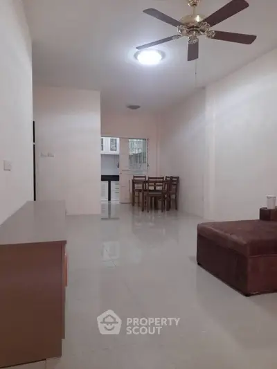 Spacious living room with ceiling fan and dining area in modern apartment.