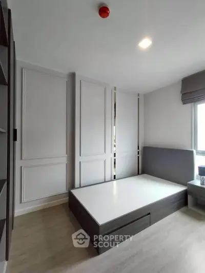 Modern bedroom with sleek design and ample natural light, featuring a stylish bed frame and elegant wall paneling.