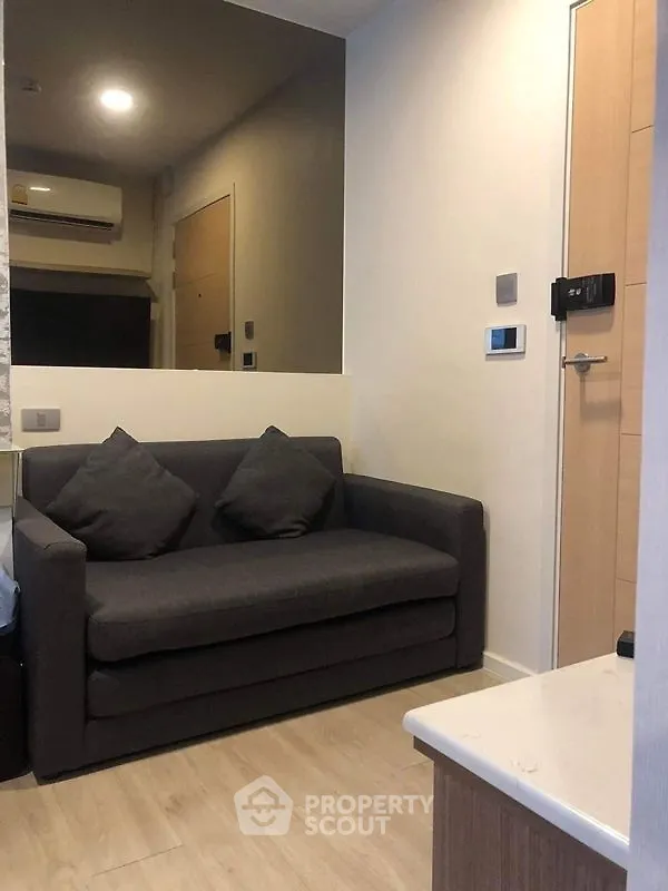 Cozy modern living room with gray sofa and wooden flooring, perfect for urban living.