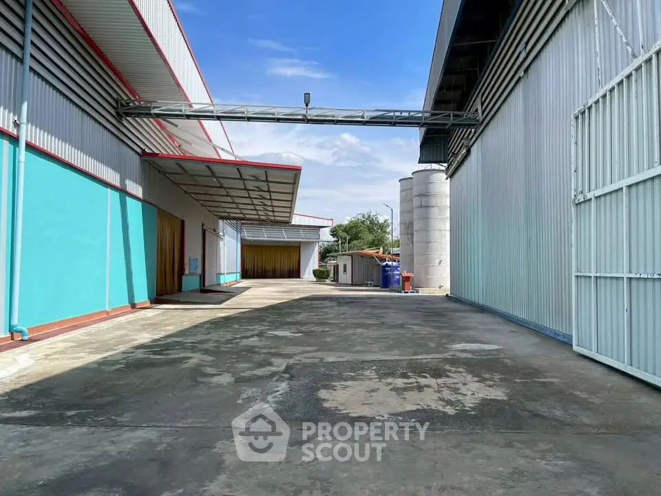 Spacious industrial warehouse exterior with ample loading area and clear blue sky.
