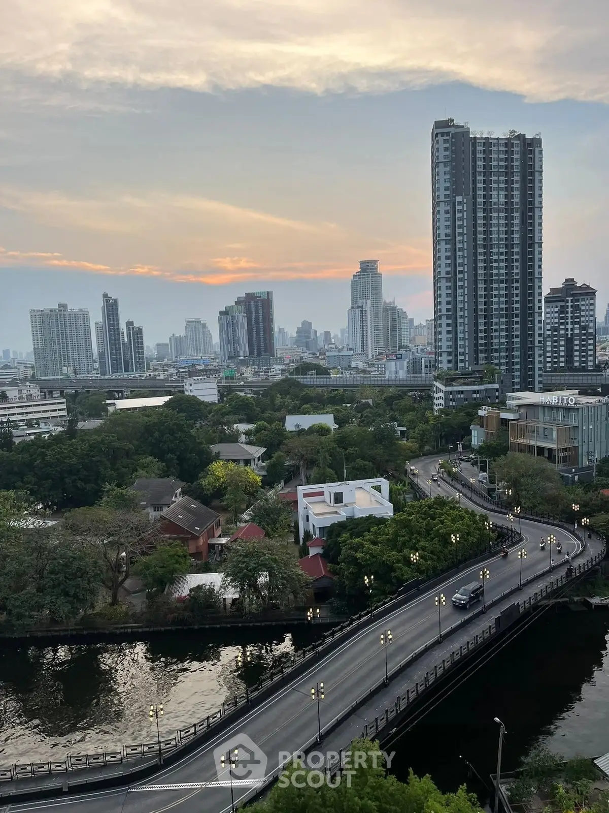 Stunning cityscape view with high-rise buildings and lush greenery at sunset.