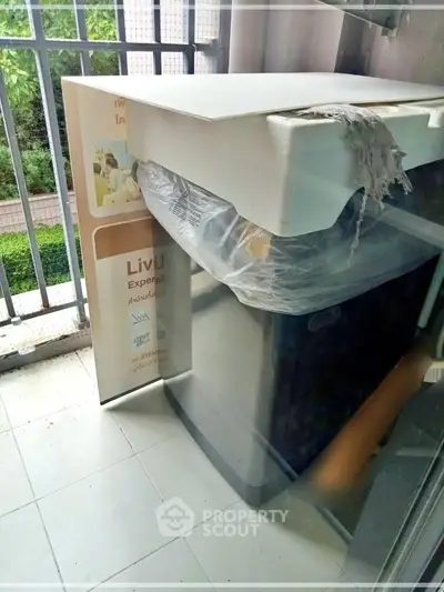 Compact balcony with washing machine and garden view, ideal for urban living.