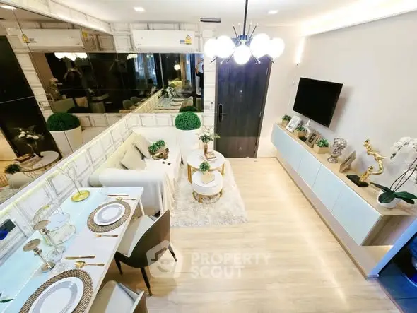 Modern living room with elegant decor and dining area, featuring stylish lighting and wall-mounted TV.