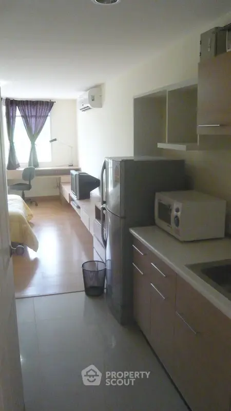 Modern studio apartment with kitchen and living area, featuring sleek appliances and natural light.