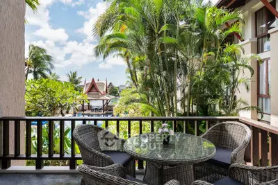 Tropical balcony with wicker furniture overlooking lush garden and pool area