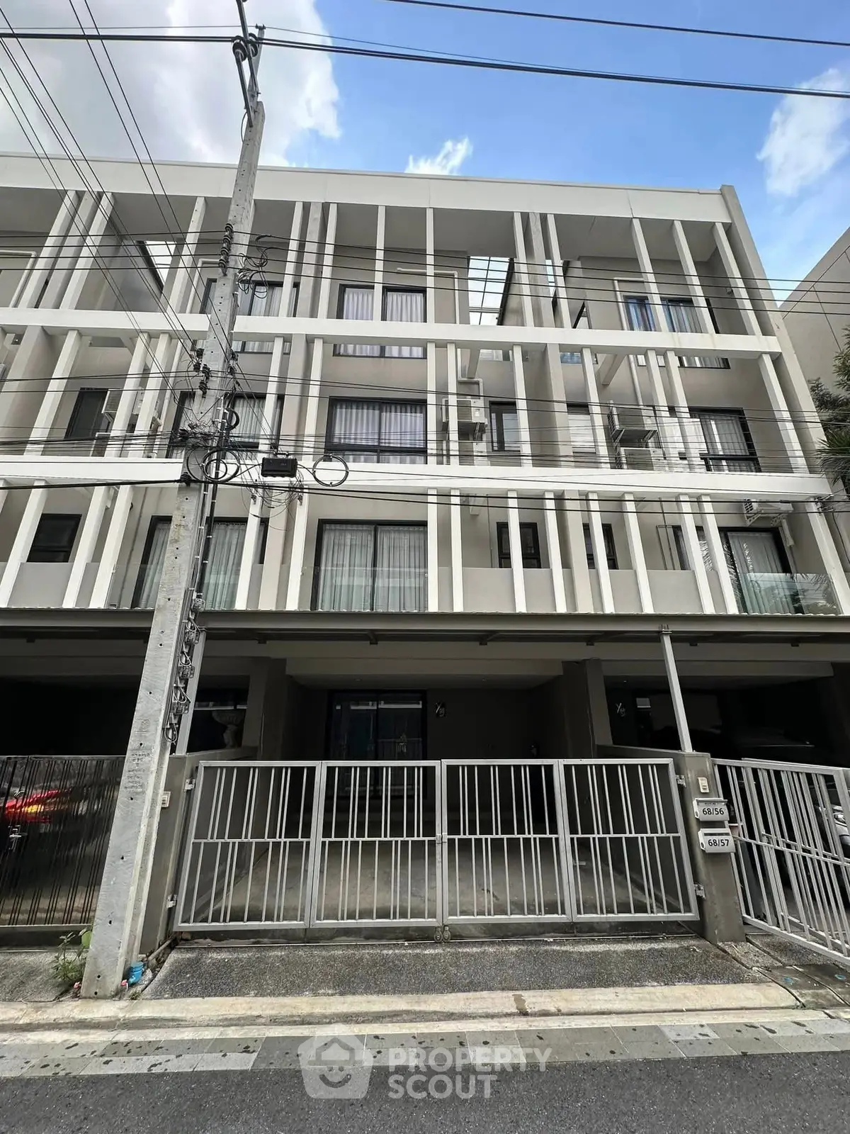 Modern multi-story building with sleek facade and gated entrance in urban setting.